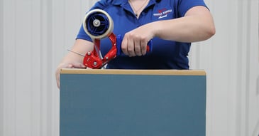 A female worker taping a box on a conveyor belt